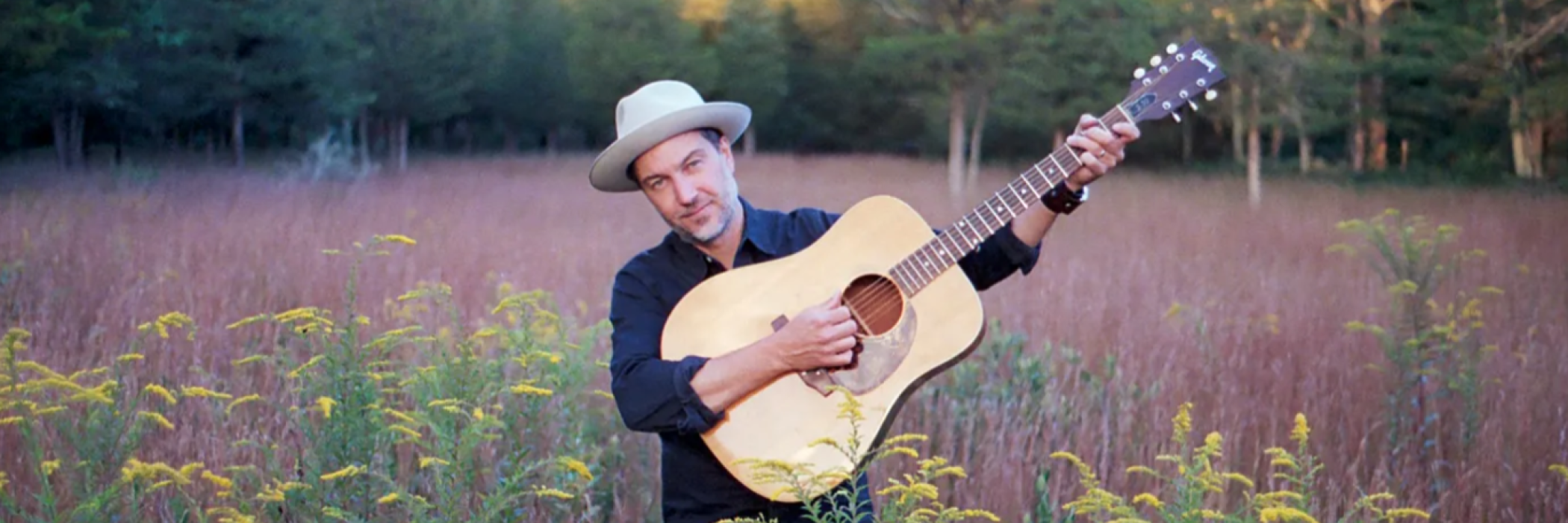 Brian Dolzani on the guitar in a field
