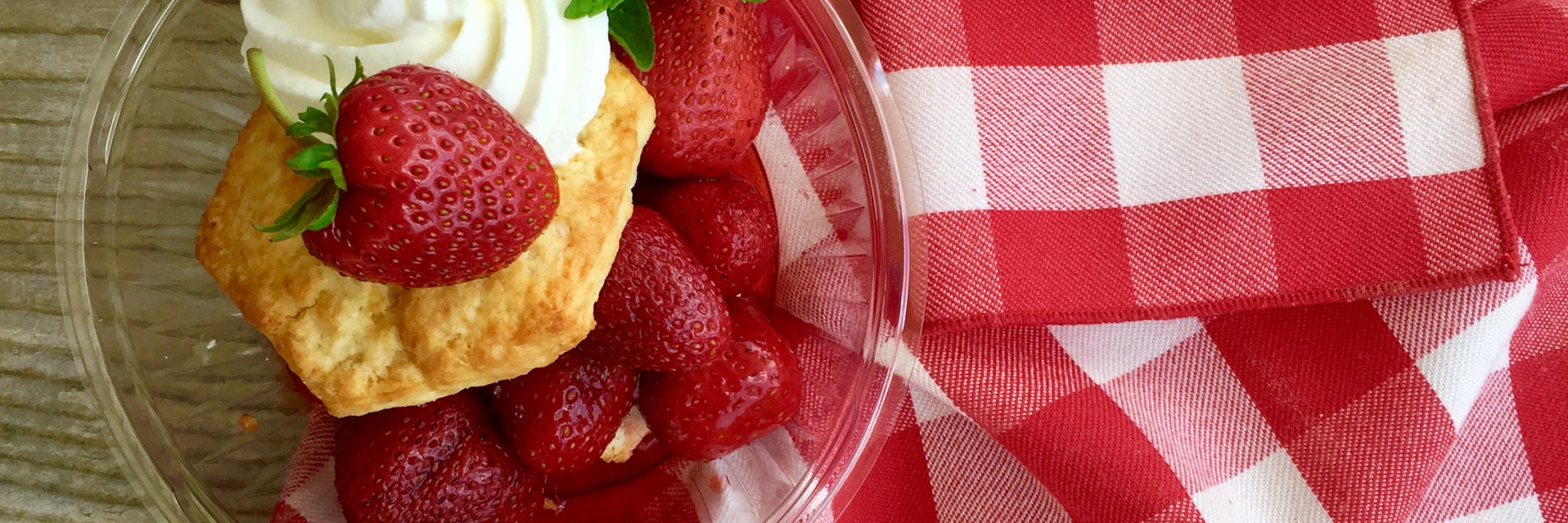 strawberry shortcake on a clear plate over red and white cloth